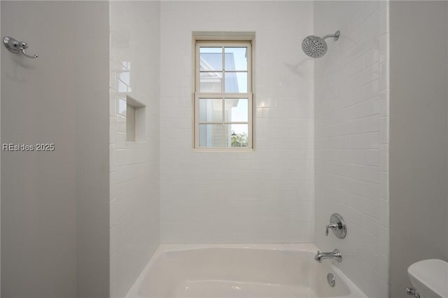 bathroom featuring tiled shower / bath and toilet