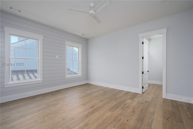 unfurnished room featuring wooden walls, ceiling fan, and light wood-type flooring