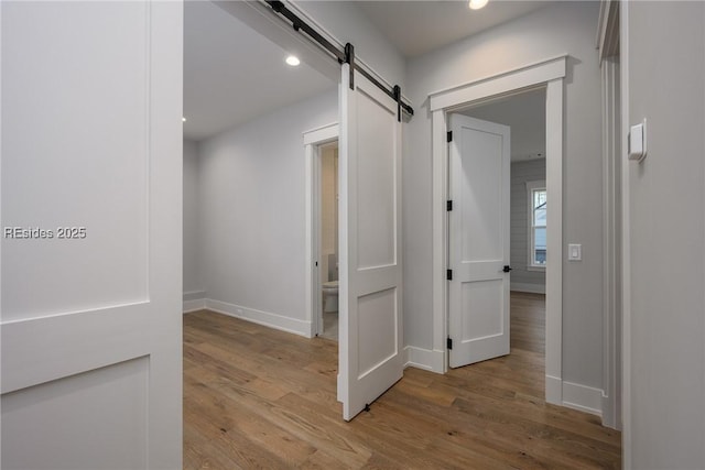 corridor with light hardwood / wood-style floors and a barn door