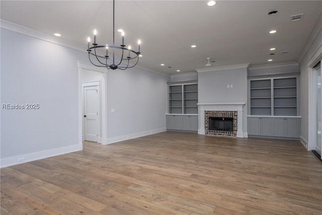 unfurnished living room with wood-type flooring, a brick fireplace, ornamental molding, and built in features