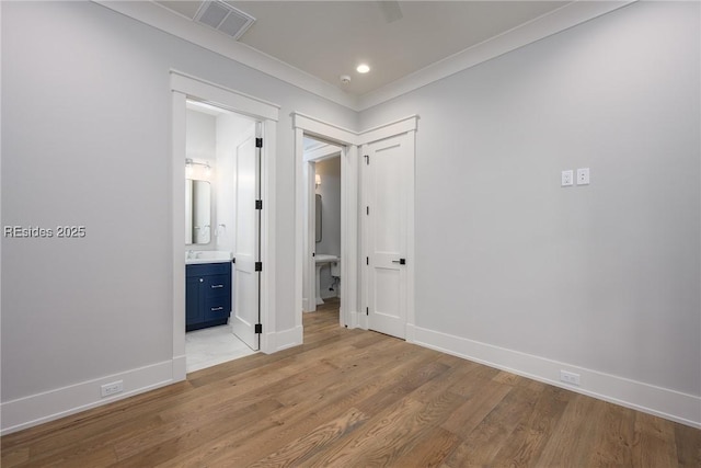 unfurnished bedroom featuring crown molding, ensuite bath, and light hardwood / wood-style flooring