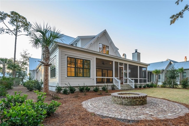 view of front facade featuring a sunroom, a front lawn, and an outdoor fire pit