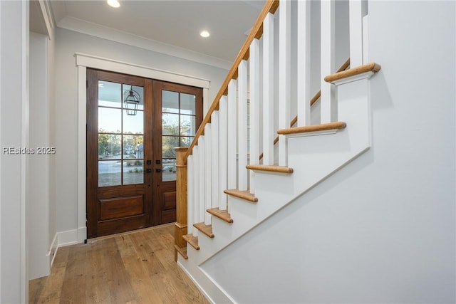 foyer entrance featuring ornamental molding, light hardwood / wood-style floors, and french doors