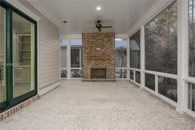 unfurnished sunroom with an outdoor brick fireplace and ceiling fan