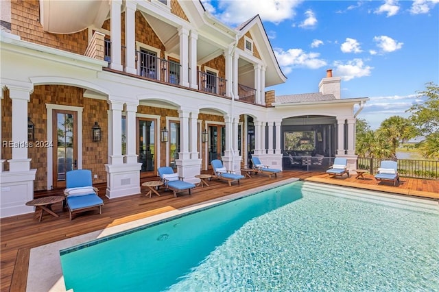 view of pool with a wooden deck and a sunroom