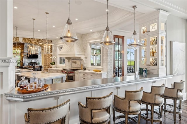 kitchen with a breakfast bar, decorative light fixtures, tasteful backsplash, white cabinetry, and double oven range