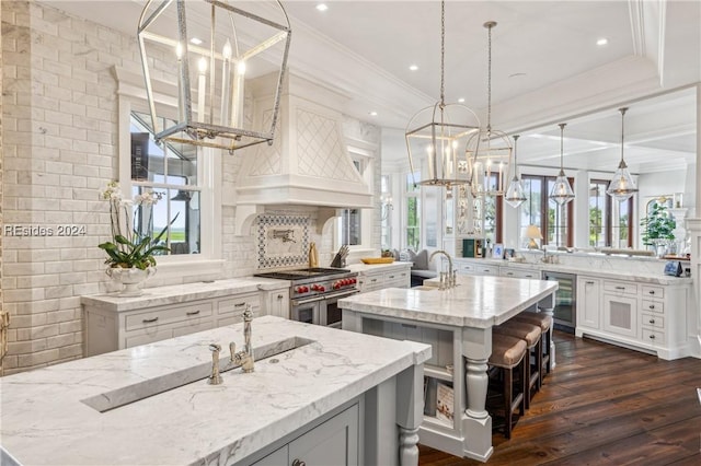 kitchen with a large island, hanging light fixtures, tasteful backsplash, light stone countertops, and beverage cooler