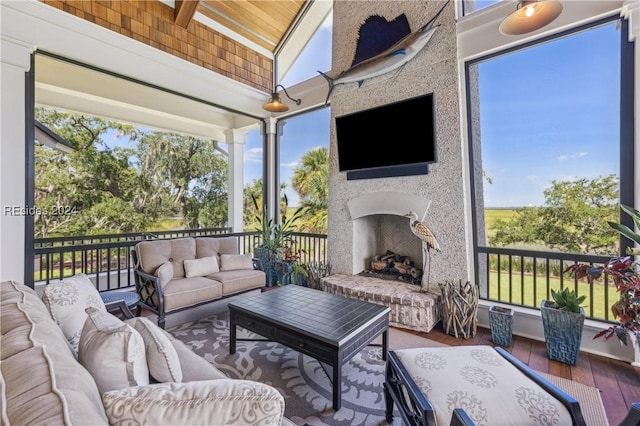 sunroom / solarium featuring a fireplace, plenty of natural light, and vaulted ceiling