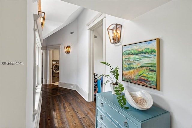 hallway featuring vaulted ceiling, washer / dryer, a notable chandelier, and dark hardwood / wood-style flooring