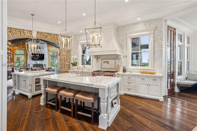 kitchen featuring a kitchen bar, decorative light fixtures, a center island with sink, and backsplash