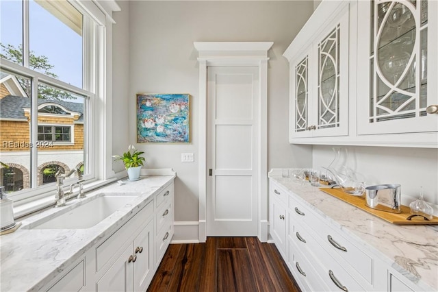 interior space with light stone countertops, sink, dark wood-type flooring, and white cabinets