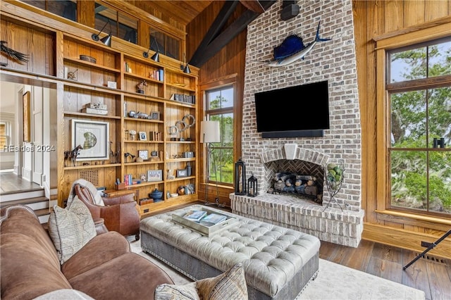 living room featuring lofted ceiling, wood ceiling, wooden walls, wood-type flooring, and a brick fireplace