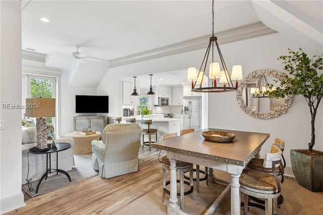 dining space with crown molding, ceiling fan with notable chandelier, and light wood-type flooring