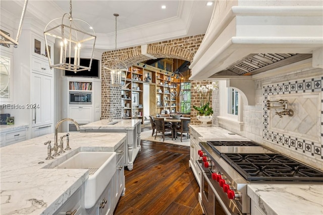 kitchen featuring double oven range, light stone countertops, and premium range hood