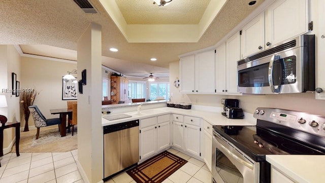 kitchen with stainless steel appliances, light tile patterned floors, a textured ceiling, and white cabinets