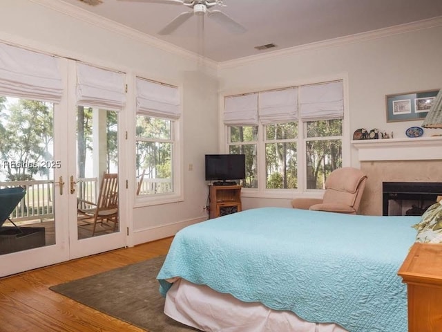 bedroom featuring multiple windows, access to exterior, wood-type flooring, and ceiling fan