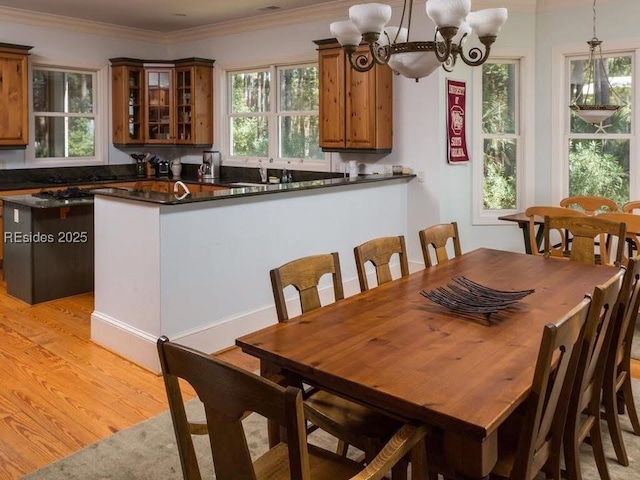 dining area featuring crown molding, a chandelier, a healthy amount of sunlight, and light wood-type flooring