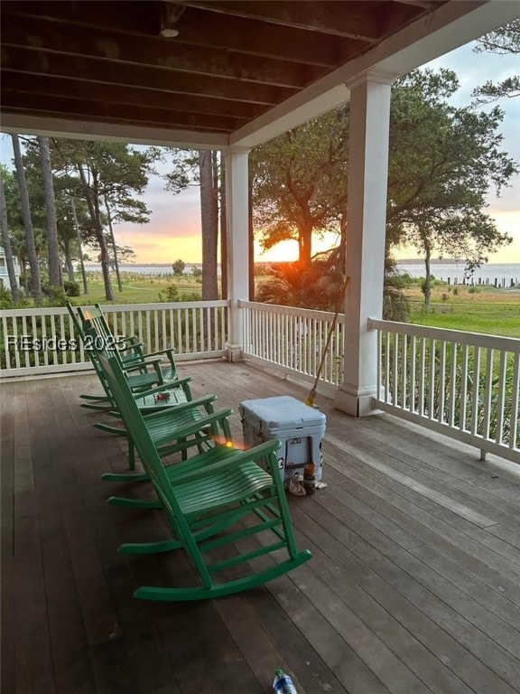 deck at dusk featuring a porch