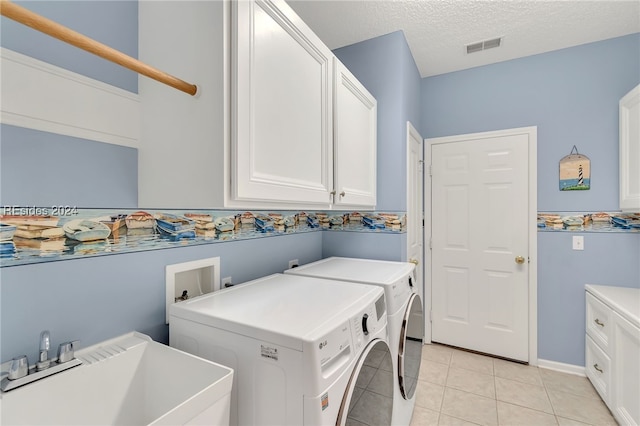 laundry area with sink, cabinets, light tile patterned floors, independent washer and dryer, and a textured ceiling