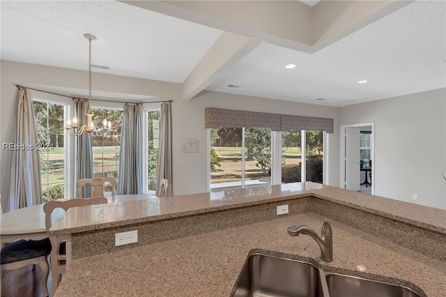 kitchen with an inviting chandelier, decorative light fixtures, sink, and a textured ceiling