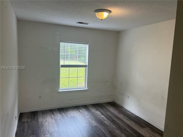 spare room featuring dark hardwood / wood-style flooring and a textured ceiling