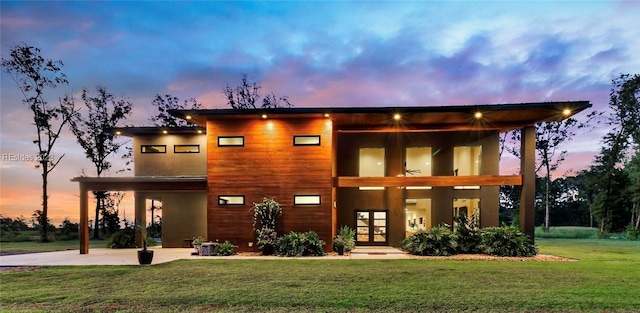 view of front of house featuring french doors, a patio area, and a lawn