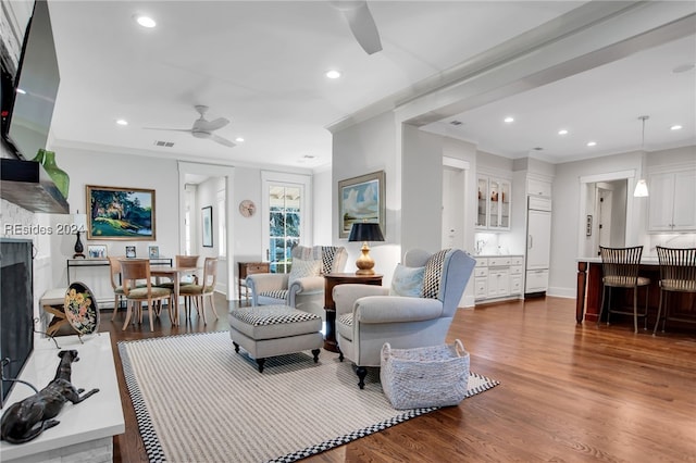 living room featuring ornamental molding, dark wood-type flooring, bar, and ceiling fan