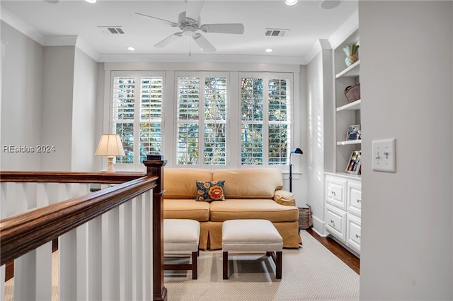 living area featuring ornamental molding, wood-type flooring, built in features, and ceiling fan