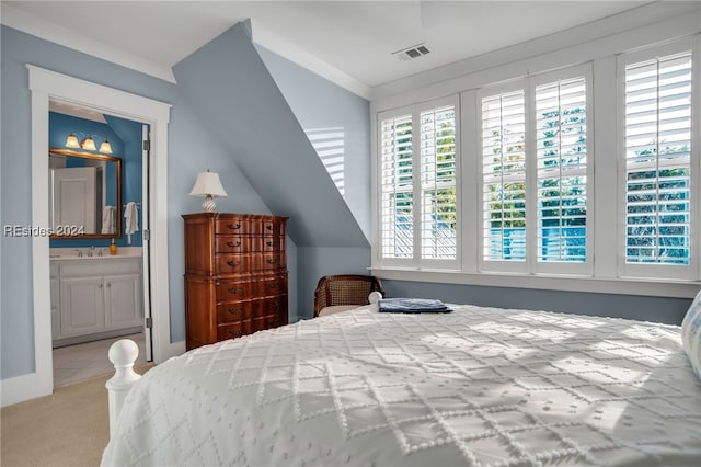 bedroom with ensuite bath, lofted ceiling, sink, and light colored carpet