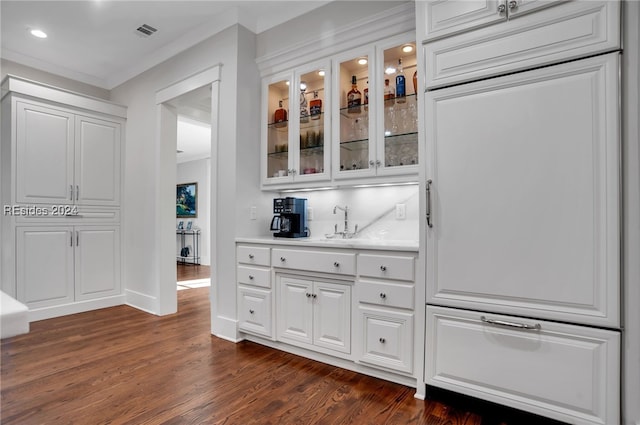 bar with ornamental molding, dark hardwood / wood-style floors, and white cabinets