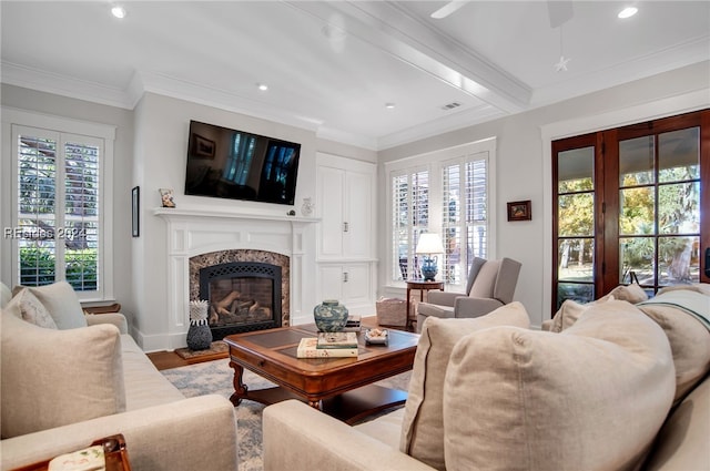 living room with crown molding, a premium fireplace, light hardwood / wood-style flooring, and a wealth of natural light