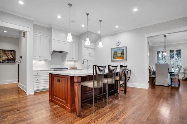 kitchen with dark wood-type flooring, white cabinetry, pendant lighting, a large island, and backsplash