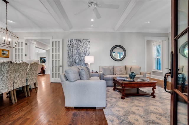 living room with ceiling fan with notable chandelier, beamed ceiling, dark hardwood / wood-style flooring, crown molding, and french doors