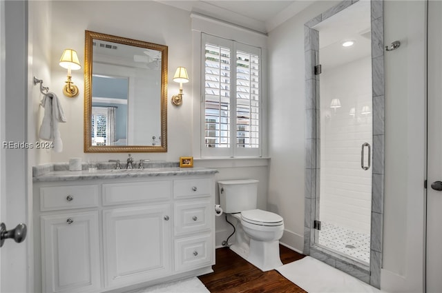 bathroom featuring crown molding, hardwood / wood-style floors, vanity, toilet, and walk in shower