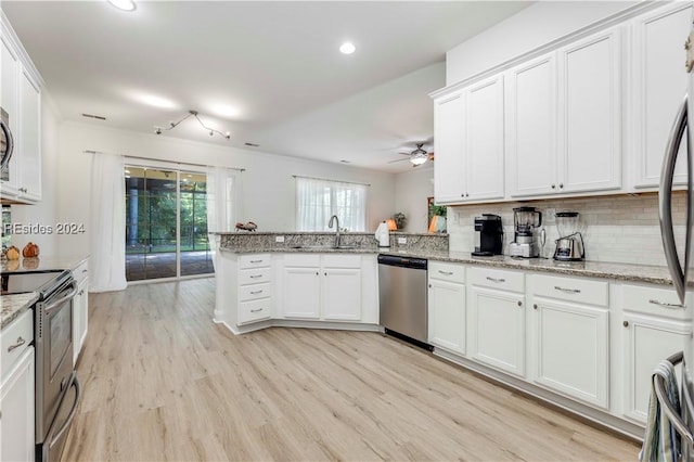 kitchen with light hardwood / wood-style floors, kitchen peninsula, white cabinets, and appliances with stainless steel finishes