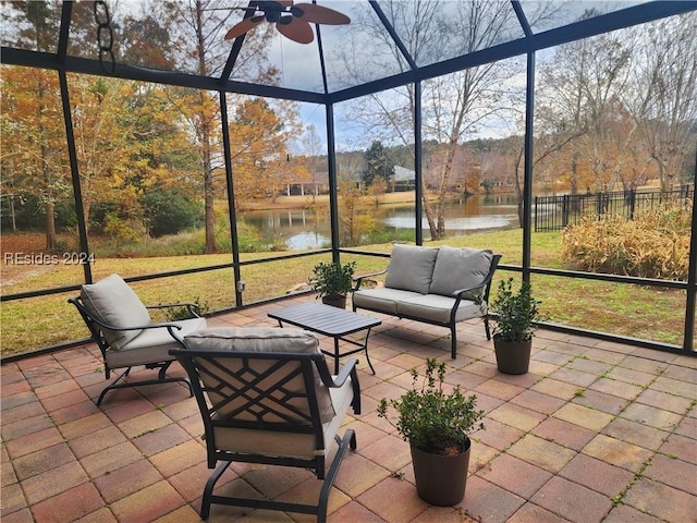 unfurnished sunroom featuring ceiling fan and a water view