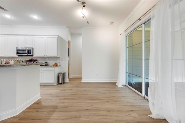 kitchen featuring white cabinetry, crown molding, tasteful backsplash, light hardwood / wood-style flooring, and light stone countertops