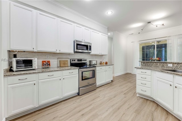 kitchen with white cabinetry, stainless steel appliances, ornamental molding, decorative backsplash, and light wood-type flooring