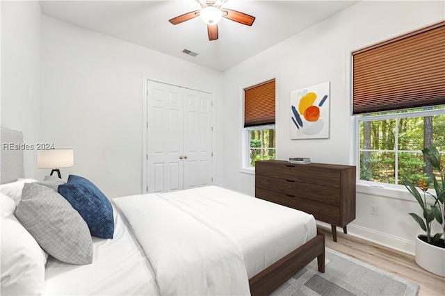 bedroom with light hardwood / wood-style floors, ceiling fan, and a closet