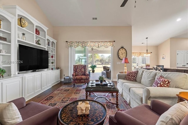 living room with dark wood-type flooring, plenty of natural light, and ceiling fan with notable chandelier