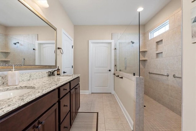 bathroom with tile patterned flooring, vanity, and tiled shower