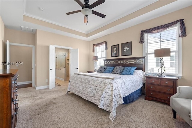 carpeted bedroom featuring crown molding, ensuite bath, ceiling fan, and a tray ceiling