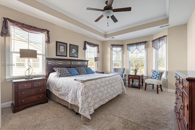 bedroom featuring light carpet, a tray ceiling, crown molding, and ceiling fan