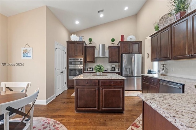 kitchen with dark brown cabinetry, decorative backsplash, stainless steel appliances, and wall chimney exhaust hood