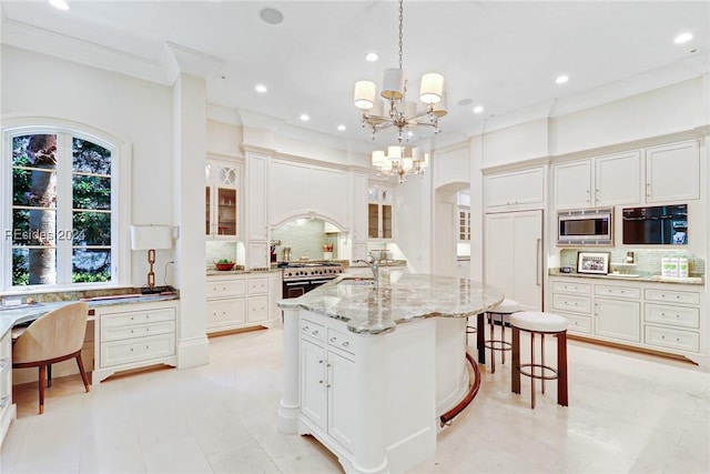 kitchen featuring hanging light fixtures, an island with sink, built in appliances, and decorative backsplash