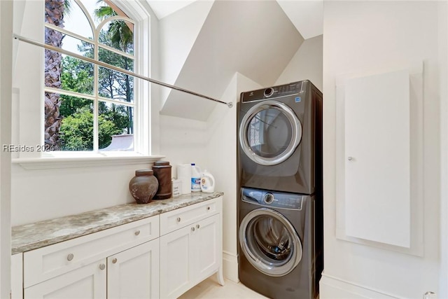 laundry room with stacked washer / dryer, plenty of natural light, and cabinets