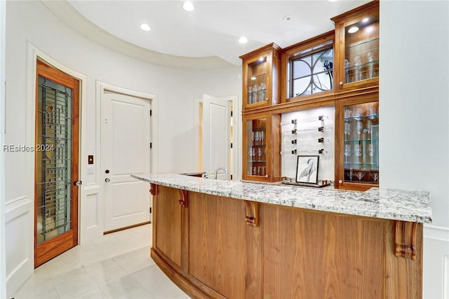 bar featuring light stone counters and light tile patterned floors