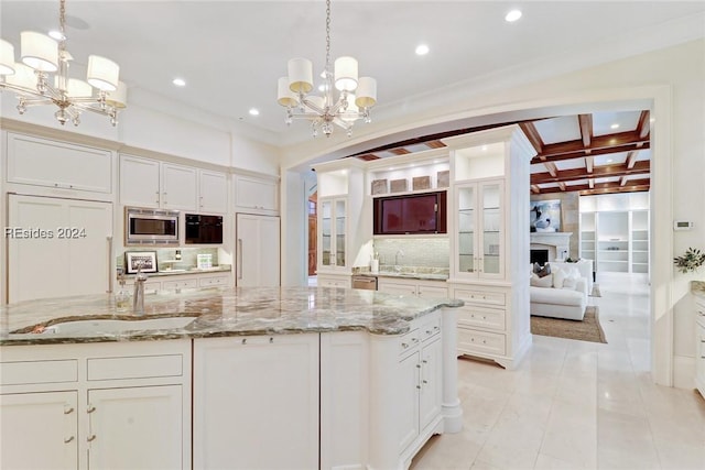 kitchen featuring pendant lighting, appliances with stainless steel finishes, an inviting chandelier, tasteful backsplash, and a large island with sink