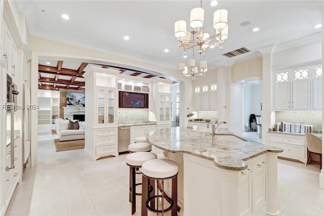 kitchen featuring pendant lighting, sink, an island with sink, and white cabinets