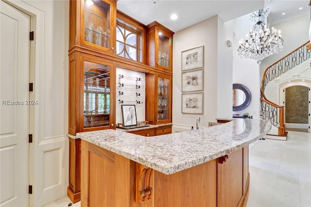 bar featuring light stone counters, plenty of natural light, a chandelier, and hanging light fixtures